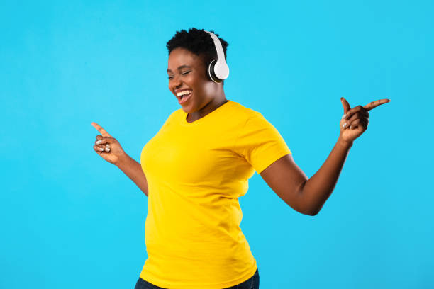 istock Black Overweight Lady Listening Music Dancing Over Blue Studio Background 1297644438