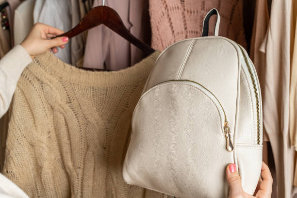 istock Woman choosing  small leather backpack, clothes in home cupboard. Season concept 1297644575