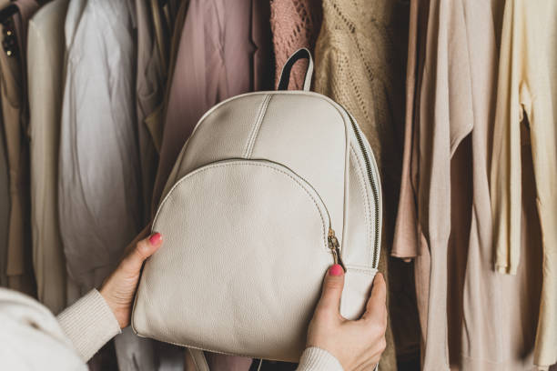 istock Woman choosing  small leather backpack, clothes in home cupboard. Season concept 1297644597