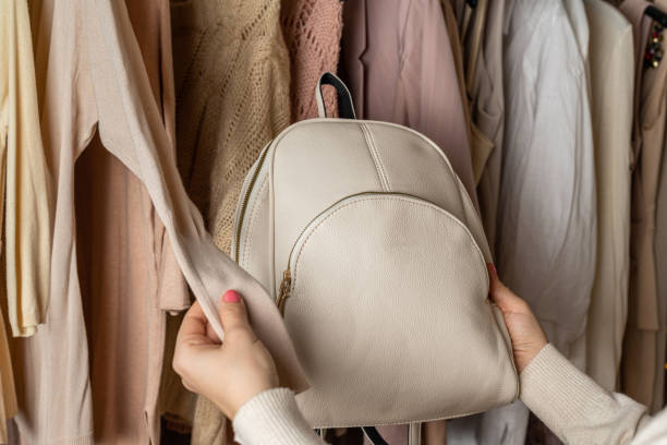 istock Woman choosing  small leather backpack, clothes in home cupboard. Season concept 1297644610