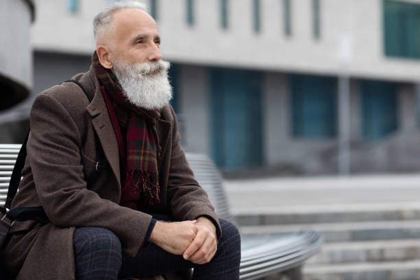 istock Good looking senior man sitting on bench next to office 1297644617