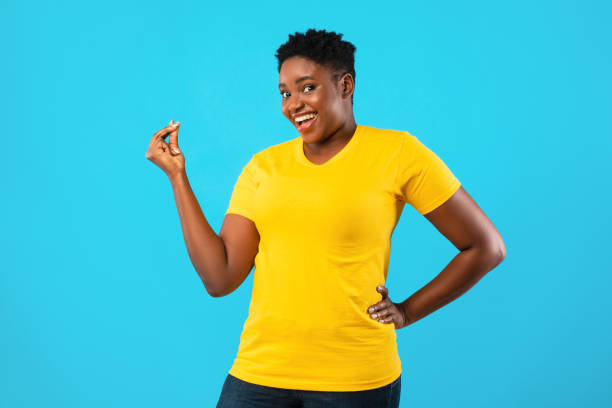 African Oversized Woman Clicking Fingers Standing Posing On Blue Background African American Oversized Woman Gesturing Clicking Fingers Standing Posing On Blue Background In Studio, Smiling To Camera. Finger Snap Gesture Concept click finger stock pictures, royalty-free photos & images