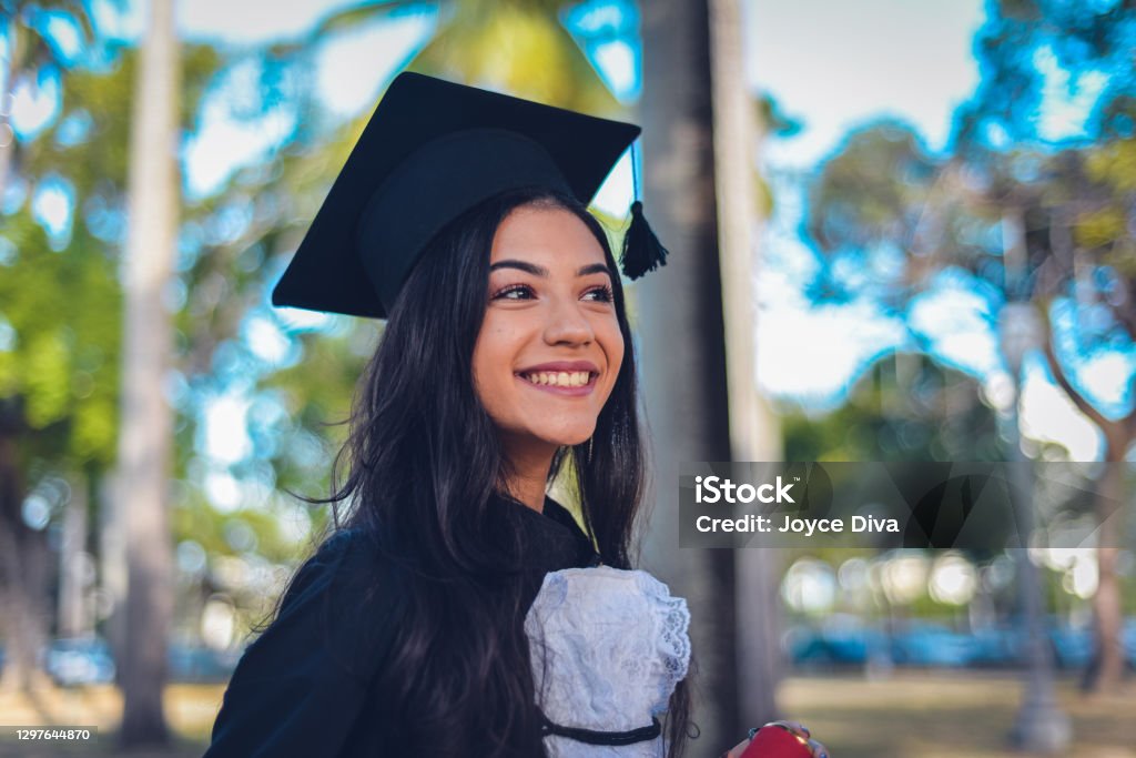 Person in College or Graduate School - High Resolution Image A young woman wearing a cap and gown, mixed race Hispanic and Caucasian. She is a university or high school graduate, smiling at the camera. Graduation Stock Photo
