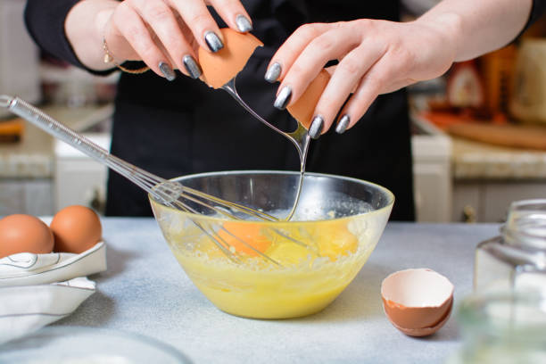 istock cook's hands break an egg over a glass bowl of dough 1297645533