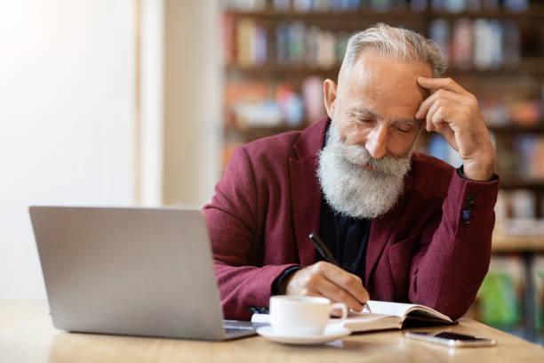 istock Aged businessman checking his agenda, working at cafe 1297645538