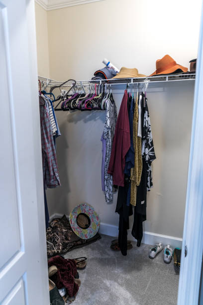 istock A mostly empty walk in messy closet with some hanging clothes and hats 1297649924