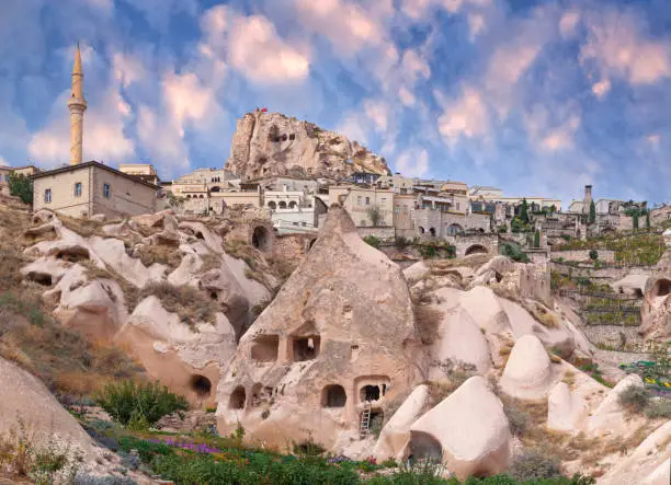 Panorama of Uchhisar town and unique geological formations in Pigeon valley at sunset in Cappadocia, Central Anatolia, Turkey.