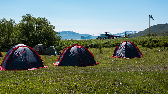 Kamchatka Peninsula, Russia - July 8, 2018: Helicopter landed near the tent camping in the Kronotsky Reserve near Kuril Lake, Kamchatka