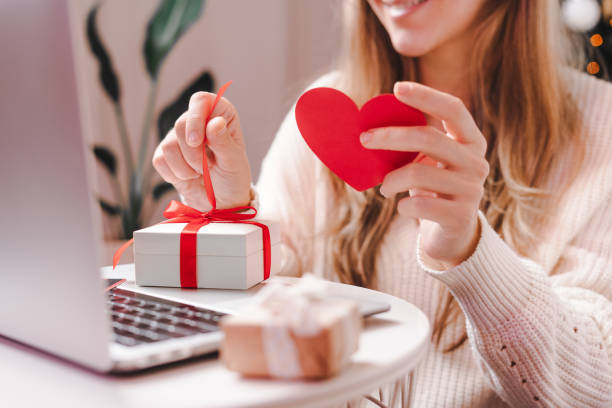 femme avec la carte et le cadeau de valentine ayant un chat vidéo sur l’ordinateur portatif - valentine present photos et images de collection