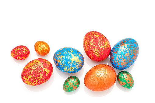 Holidays: overhead view of hand painted multi colored Easter eggs isolated on white background. The composition is at the bottom of an horizontal frame leaving useful copy space for text and/or logo. High resolution 42Mp studio digital capture taken with Sony A7rII and Sony FE 90mm f2.8 macro G OSS lens