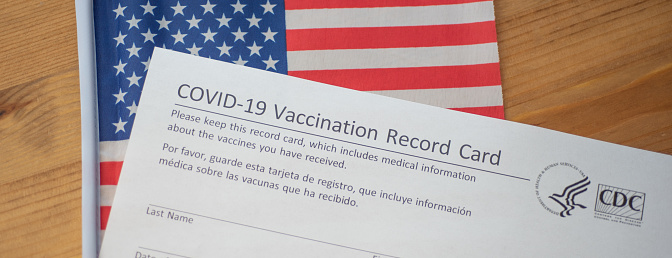 Washington, DC, USA - December, 23, 2020: Fragment of COVID-19 Vaccination Record Card by CDC on Flag of USA background. Banner photo.