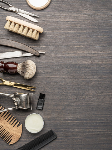 Classic grooming and hairdressing tools on wooden background. Top view on barbershop instruments  laying on dark wooden table.