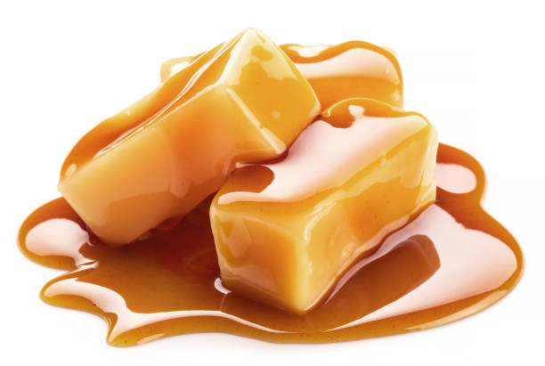 istock Caramel candies covered with melted sugar caramel isolated on white background. 1297653400