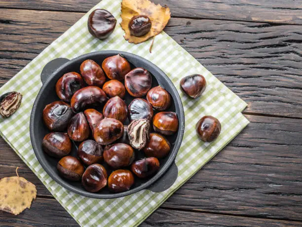 Photo of Roasted edible chestnut fruits in the pan. Top view.