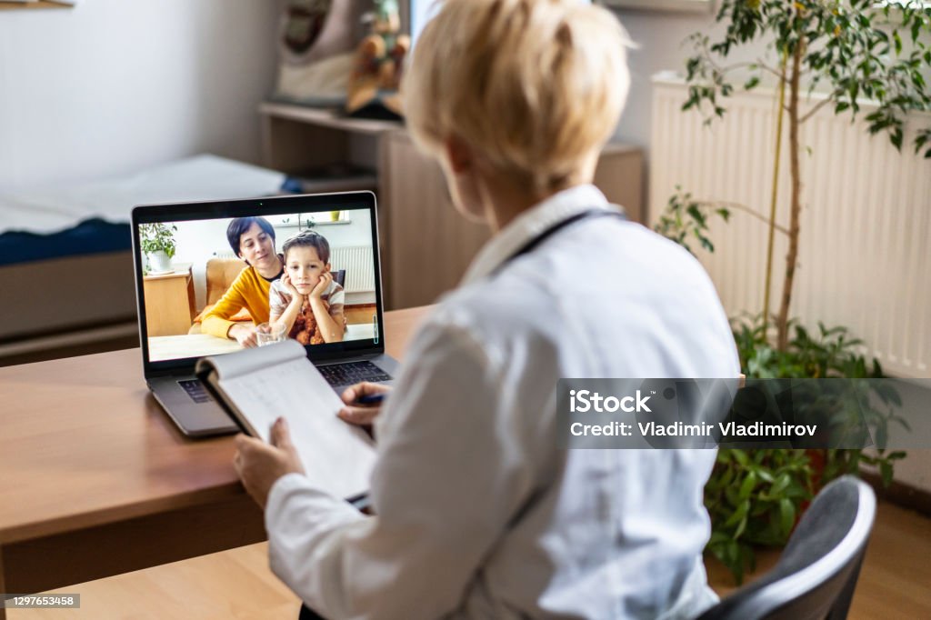 Female Paediatrician writing prescriptions to his small patient and his mother during a video call Paediatrician explains prescriptions to his small patient and his mother during a video call Doctor Stock Photo
