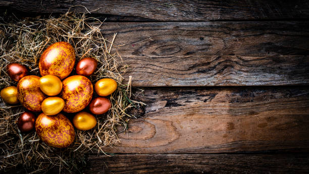 istock Straw nest with gold and bronze colored Easter eggs on rustic wooden table. Copy space 1297655242