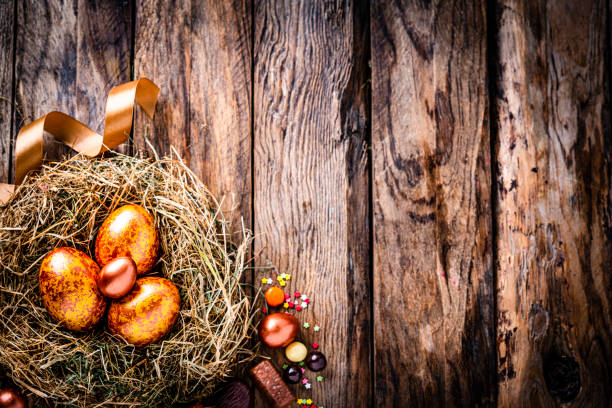 istock Gold and bronze colored Easter eggs and chocolate candies on rustic wooden table. Copy space 1297655836