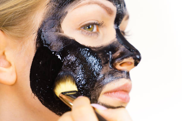 istock Woman applying black mud mask to face 1297657322