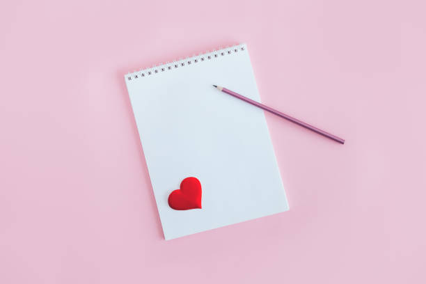 istock Notebook with blank page, pencil and red heart on a pink background. 1297658260