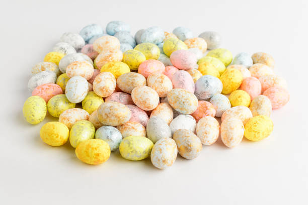 istock Heap of mixed chocolate coated Easter eggs candies isolated on a white table, tasty sugary dessert for children 1297659505