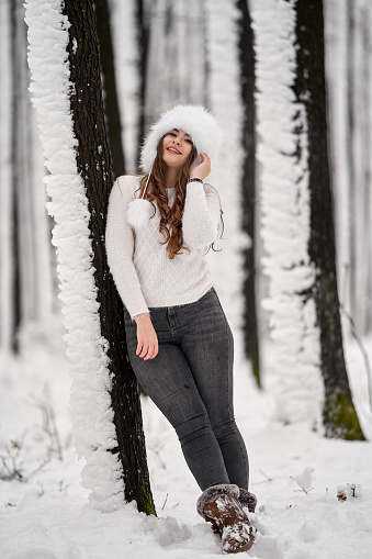 Young caucasian woman having fun playing in the snow in the forest
