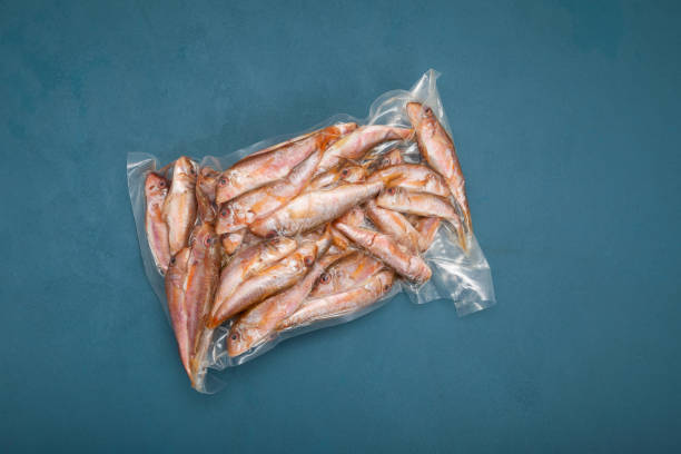 istock Frozen fish Red mullet (Goatfish) in plastic bag on blue background with copy space. Top view. Mullus barbatus found in Mediterranean Sea, Black Sea and eastern North Atlantic Ocean 1297663850
