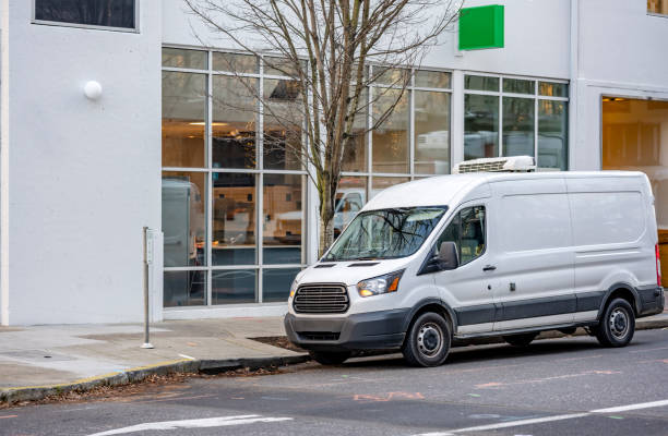 istock Commercial compact cargo van with rooftop air conditioner for carry chilled products standing on the city street unloading delivered cargo to the store 1297666232