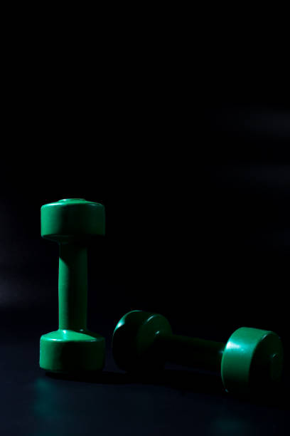 istock Two green dumbbells. Little dumbbells on black background 1297666555
