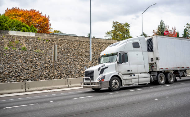 istock White big rig semi truck with grille guard transporting cargo in refrigerator semi trailer running on down hill road with gravel hillside 1297669276