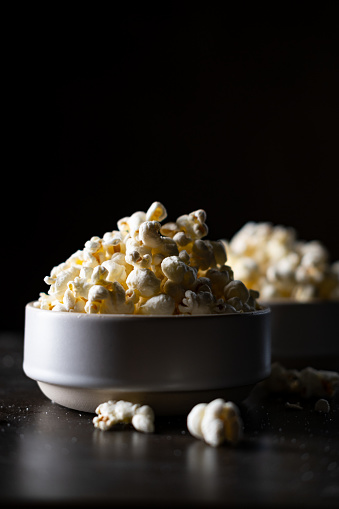 Movie night for two, buttered salty popcorn on a dark table. A lot of empty space for text.