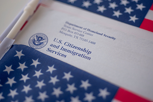 Washington, DC, USA - September, 16, 2019: Letter (Envelope) from USCIS between two  USA flags on American colors background.