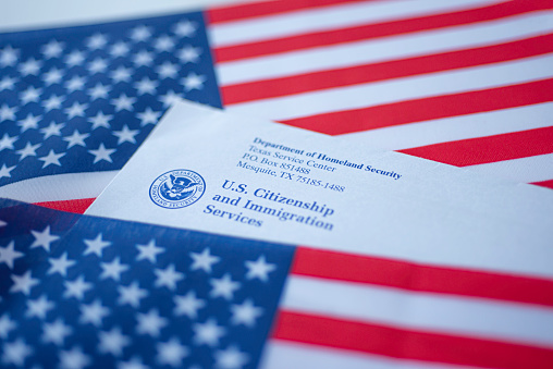 Washington, DC, USA - September, 16, 2019: Letter (Envelope) from USCIS covered in flags of USA. Close up view.