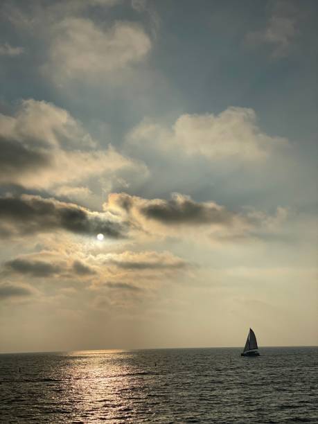 istock Sailboat in the distance with dramatic clouds 1297669509