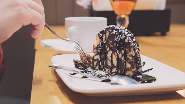istock Woman in cafe eats cake with fork. Nearby cup coffee 1297671145
