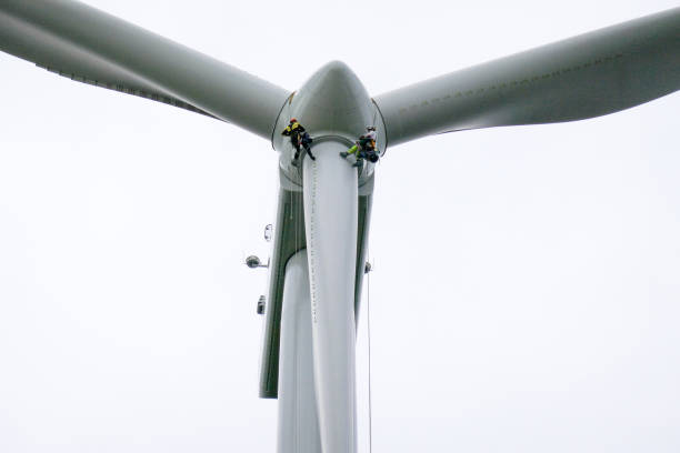 istock View from bottom on wind-turbine and two rope access technicians, industrial climbers rappelling down from hub on blade on the ropes, doing inspection and blade repair 1297674475