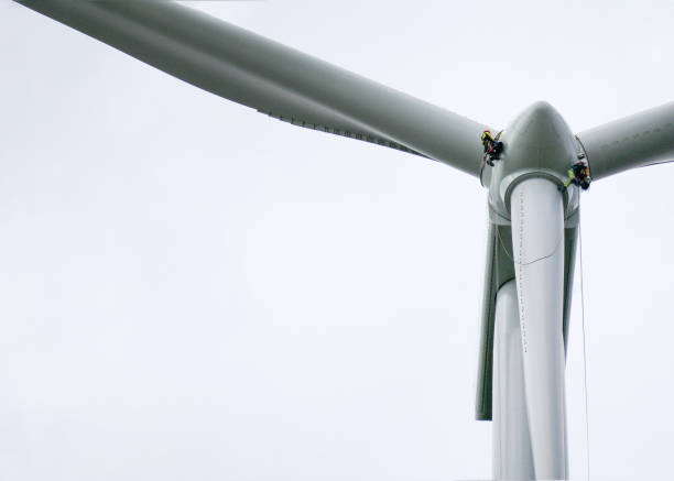 istock View from bottom on wind-turbine and two rope access technicians, industrial climbers rappelling down from hub on blade on the ropes, doing inspection and blade repair 1297674476