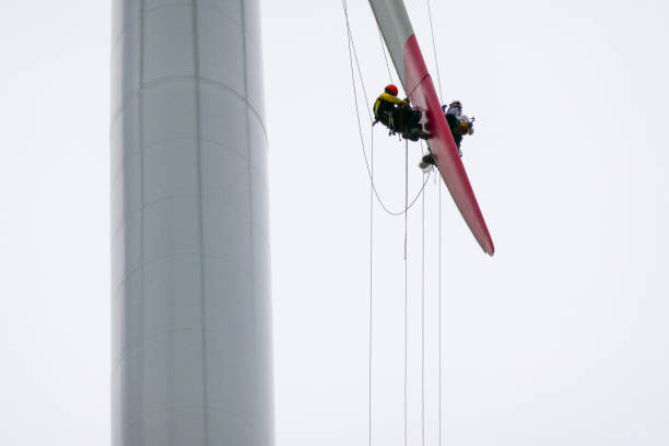 istock Two rope access technicians working on the tip of the blade, hanging on the ropes, doing inspection and tower is behind them 1297674520