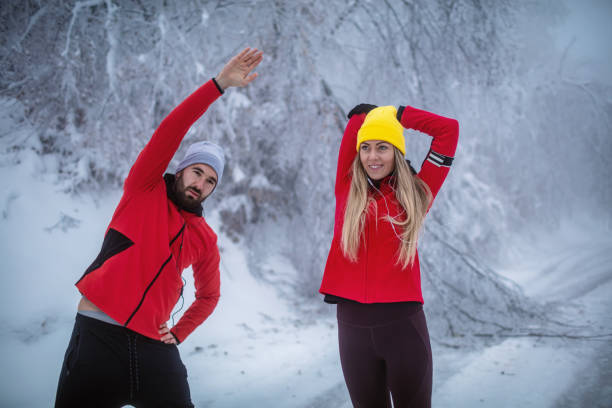 Athlete young couple exercise outdoor, they are stretching after running. Fogy and cold weather.