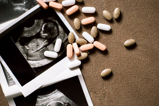 foto del feto en una ecografía y pocas píldoras sobre fondo marrón - vitamin e capsule medicine pill fotografías e imágenes de stock