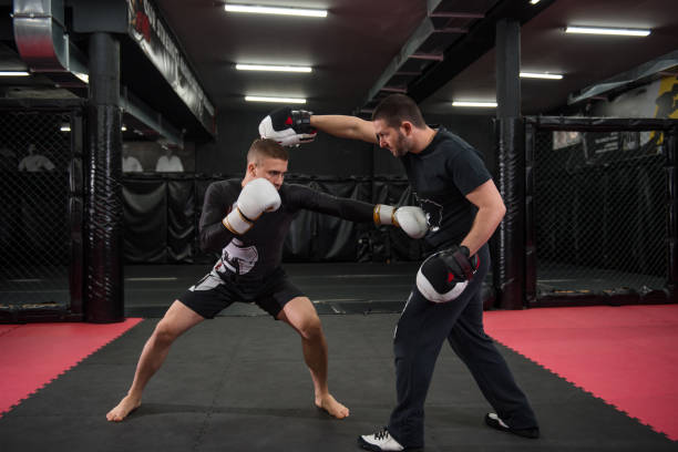 Male fighter training with his trainer Caucasian fighter at kickboxing training practicing punching, kicking and sparring with his trainer. boxing gym stock pictures, royalty-free photos & images