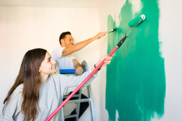 istock Side view of a married couple using a paintbrush and roller 1297682450