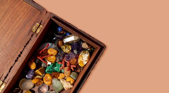 Mixed natural gemstones in wooden chest. Various rough and polished stones. Gemstone collection.