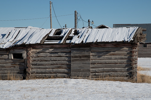 Snow covered log cabin and old ranch equipment