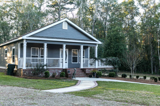 istock Small blue gray mobile home with a front and side porch with white railing 1297700096