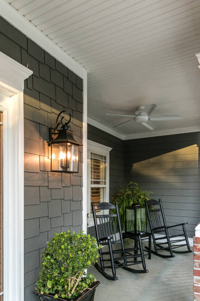 un gran porche delantero de una casa gris tradicional de nueva construcción con mecedoras - front porch fotografías e imágenes de stock