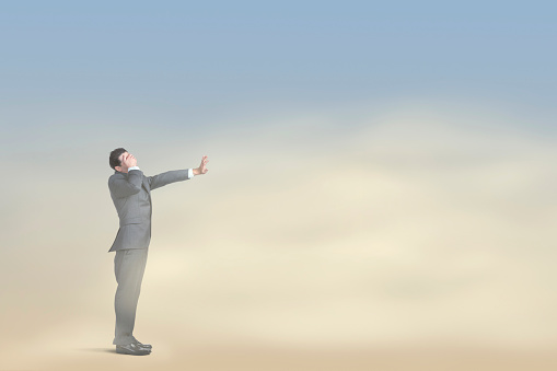 A businessman covers his eyes and tries to block the unrelenting sand and wind as he stands in a dust storm.