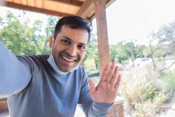 istock Handsome young adult man smiles while waving during video call 1297709491