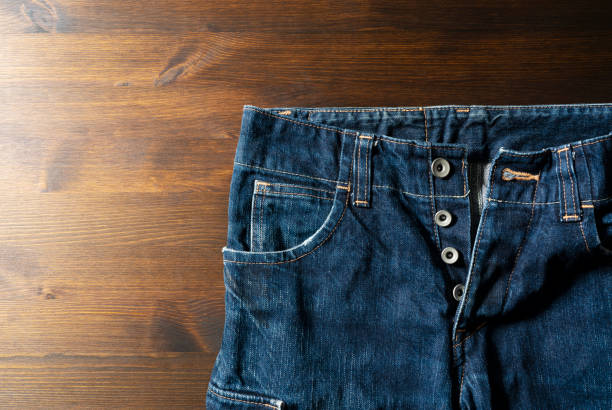istock Button fly blue jeans set against a wooden background with copy space 1297709684