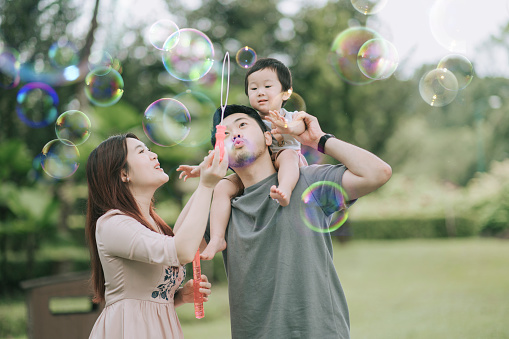 asian chinese young family playing bubble enjoying picnic time outdoor during weekend