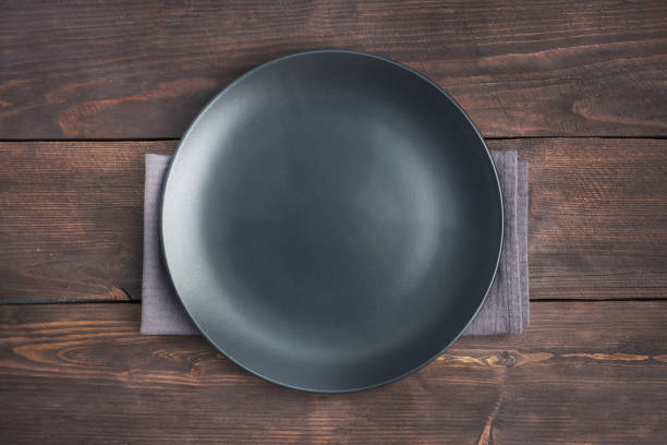 istock Empty black plate on wooden rustic background. Top view with copy space. 1297717401
